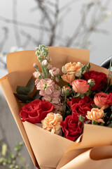 A bright bouquet of flowers in beige packaging. Red roses, Mattiol, Ranunkulus, bush cloves