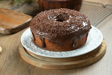 Brazilian carrot cake with chocolate frosting on wooden table with carrots in the background