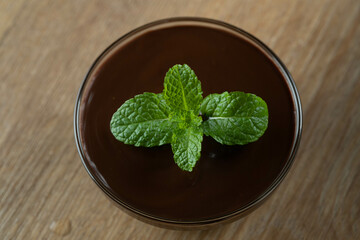 chocolate sauce mousse with mint in glass jar on wooden table. Top view