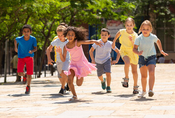 Team of positive kids running in race in the street and laughing outdoors