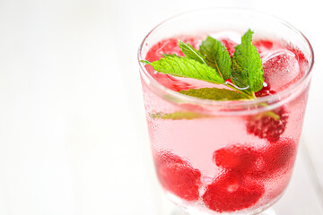 Raspberry cocktail.Summer drink.raspberry pink drink.Ice cubes with raspberries in a glass with mineral water, berries and raspberry leaves on a white table. refreshing cocktail. 