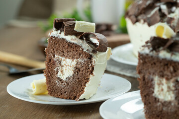 Close up piece of White chocolate and dark chocolate cake two loves on wooden table. Birthday and wedding cake
