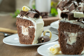 Close up piece of White chocolate and dark chocolate cake two loves on wooden table. Birthday and wedding cake