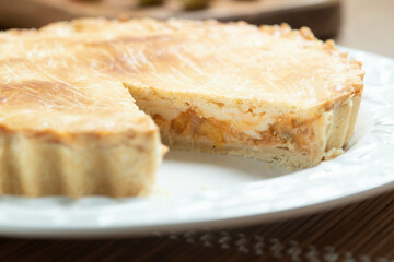 Close up piece of Chicken pie with cottage cheese, tomatoes, onion and olives on wooden table and white plate.