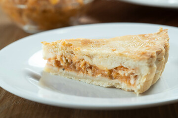 Close up piece of Chicken pie with cottage cheese, tomatoes, onion and olives on wooden table and white plate.