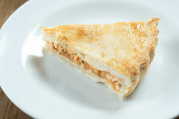 Close up piece of Chicken pie with cottage cheese, tomatoes, onion and olives on wooden table and white plate.