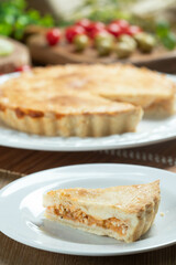 Close up piece of Chicken pie with cottage cheese, tomatoes, onion and olives on wooden table and white plate.