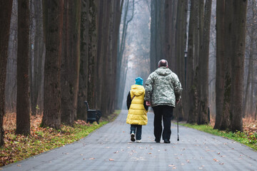 Fototapeta premium Grandfather and granddaughter walking together in the park