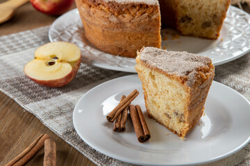 piece of sponge cake or chiffon cake with apples so soft and delicious sliced ​​with ingredients: cinnamon, eggs, flour, apples on wooden table. Home bakery concept for background and wallpaper