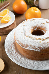 Moist orange fruit cake on plate with orange slices on wooden table. Delicious breakfast, traditional English tea time. Orange cake recipe.