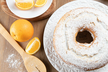 Moist orange fruit cake on plate with orange slices on wooden table. Delicious breakfast, traditional English tea time. Orange cake recipe. Top view