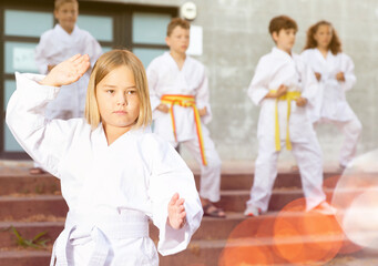 Fototapeta na wymiar Little girl throws a punch at martial arts practice