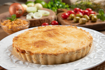 Chicken pie with cottage cheese, tomatoes, onion and olives on wooden table and white plate