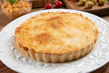 Chicken pie with cottage cheese, tomatoes, onion and olives on wooden table and white plate