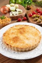 Chicken pie with cottage cheese, tomatoes, onion and olives on wooden table and white plate