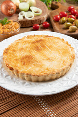 Chicken pie with cottage cheese, tomatoes, onion and olives on wooden table and white plate
