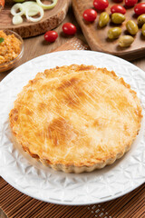 Chicken pie with cottage cheese, tomatoes, onion and olives on wooden table and white plate