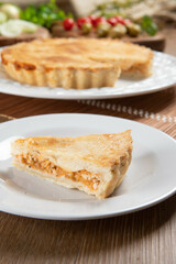 Close up piece of Chicken pie with cottage cheese, tomatoes, onion and olives on wooden table and white plate