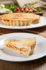 Close up piece of Chicken pie with cottage cheese, tomatoes, onion and olives on wooden table and white plate