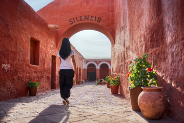 Turista latina caminando de espaldas entrando al arco Silencio del monasterio Santa Catalina en...