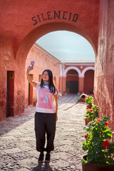 Turista latina haciéndose una selfie bajo el arco silencio del monasterio Santa Catalina en Arequipa