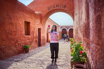 Turista latina haciéndose una selfie bajo el arco silencio del monasterio Santa Catalina en Arequipa - obrazy, fototapety, plakaty