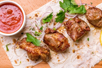 skewers of mutton flesh with red onion and tomato sauce on the board top view macro close up