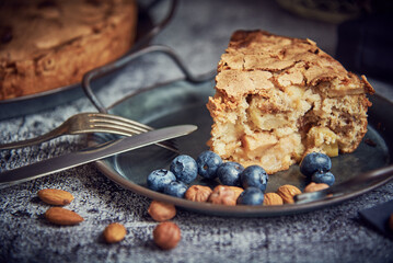 Homemade apple pie on a metal platter, decorated with blueberries and nuts. Food background.