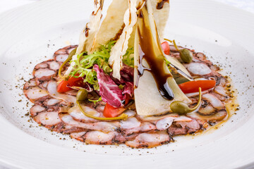 carpaccio of octopus with parmesan and vegetables on a white plate macro close up