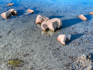 river rocks reflection shadows calm still clear blue water riverbed