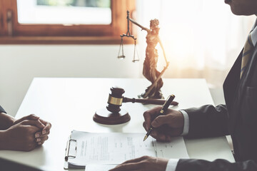 Business woman and lawyers discussing contract papers with brass scale on wooden desk in office. Law, legal services, advice, Justice concept.
