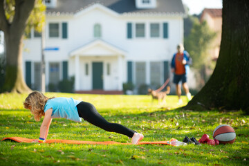 Kid doing push-ups sport exercises in park. Sport, healhty lifestyle, training, active leisure outdoor. Kid pushing up. Athletic boy is pushing up on the green grass. Sport kids.