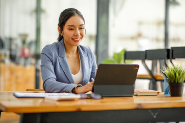 Good looking young Asian woman in pants jacket and tie working with documents in the office