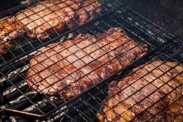 Selective focus of juicy beef steaks grilling on barbecue grid with smoke. High-quality photo