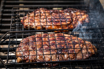 Selective focus of juicy beef steaks grilling on barbecue grid with smoke. High-quality photo
