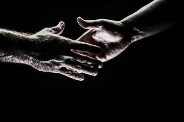 Handshake. Men holding hands isolated on black. Connection and human relations. Male hands rescue. Friendly handshake, friends greeting, friendship. Rescue, helping gesture or hands. Helping hand.