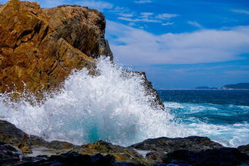 Dramatic scene with fantastic big rocks and ocean waves. Beauty world landscape with blue sky background.