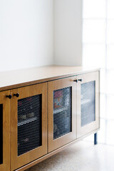 Wooden shoe cabinet with black industrial metal mesh for ventilation. Soft focus image.