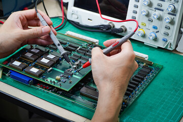 engineer is examining a circuit board with a digital storage oscilloscope.