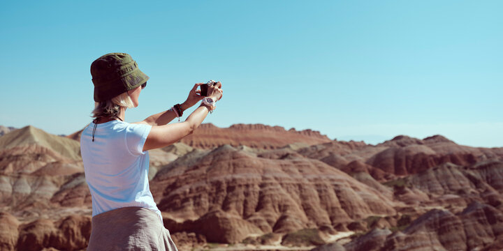 rear view of asian female tourist taking a photo in geopark using cellphone