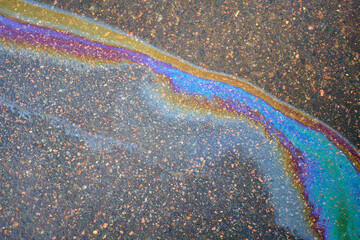 Oil stain on the asphalt, rainbow-shaped colored gasoline stains on an asphalt road
