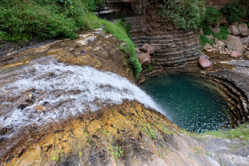 A beautiful flowing waterfall, circular water swimming hole with turquoise water surrounded by cascade rocks in the districts, a popular tourism spot, East Timor