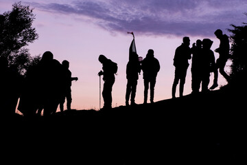 Fototapeta na wymiar Silhouetted people reach the summit of mountain at dusk with beautiful purple sunrise sky, groups of people reach the top of Mt Ramelau in East Timor, Southeast Asia