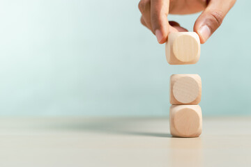 Concept of education and development. Hand picking blank wooden cube block sort on table use for...