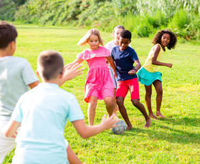 Fototapeta premium Group of barefoot kids playing football on grass. They're kicking ball and having fun.