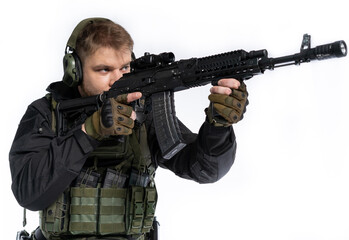 Fototapeta premium airsoft player in full gear with GG RK74 fire series guns. a man in headphones, a bulletproof vest, with a backpack and a belt, aims his machine gun to the side. profile. White background.