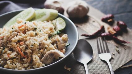 Pork fried rice is a common street food in Thailand. Served on a black wooden table.