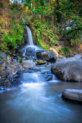 water flow from waterfalls and rocks natural water with rocks around greenery background
