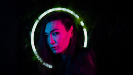 Portrait of an Asian man against the background of a circular lamp in the studio with neon light. 