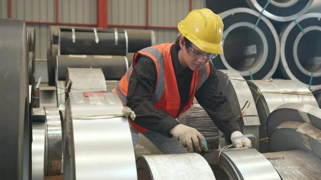 Industrial worker measuring detail and quality control of roll metal sheet roof with tape measure before shipment to customer at factory warehouse manufacture